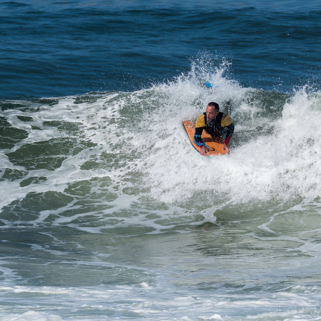 Photo of what appears to be a man bodyboarding on a wave in the ocean.