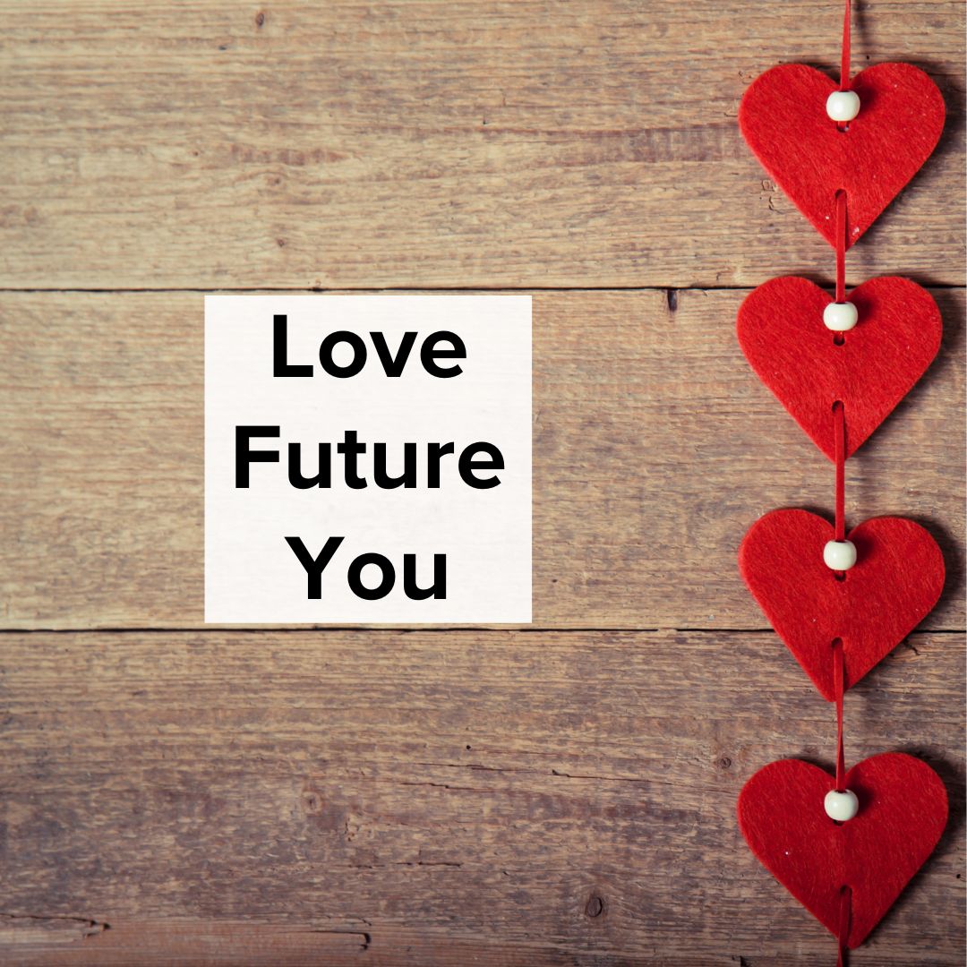 Shiplap wall with four hearts with white beads hung on the right. A sign in the middle in black font on a white background says: Love Future You