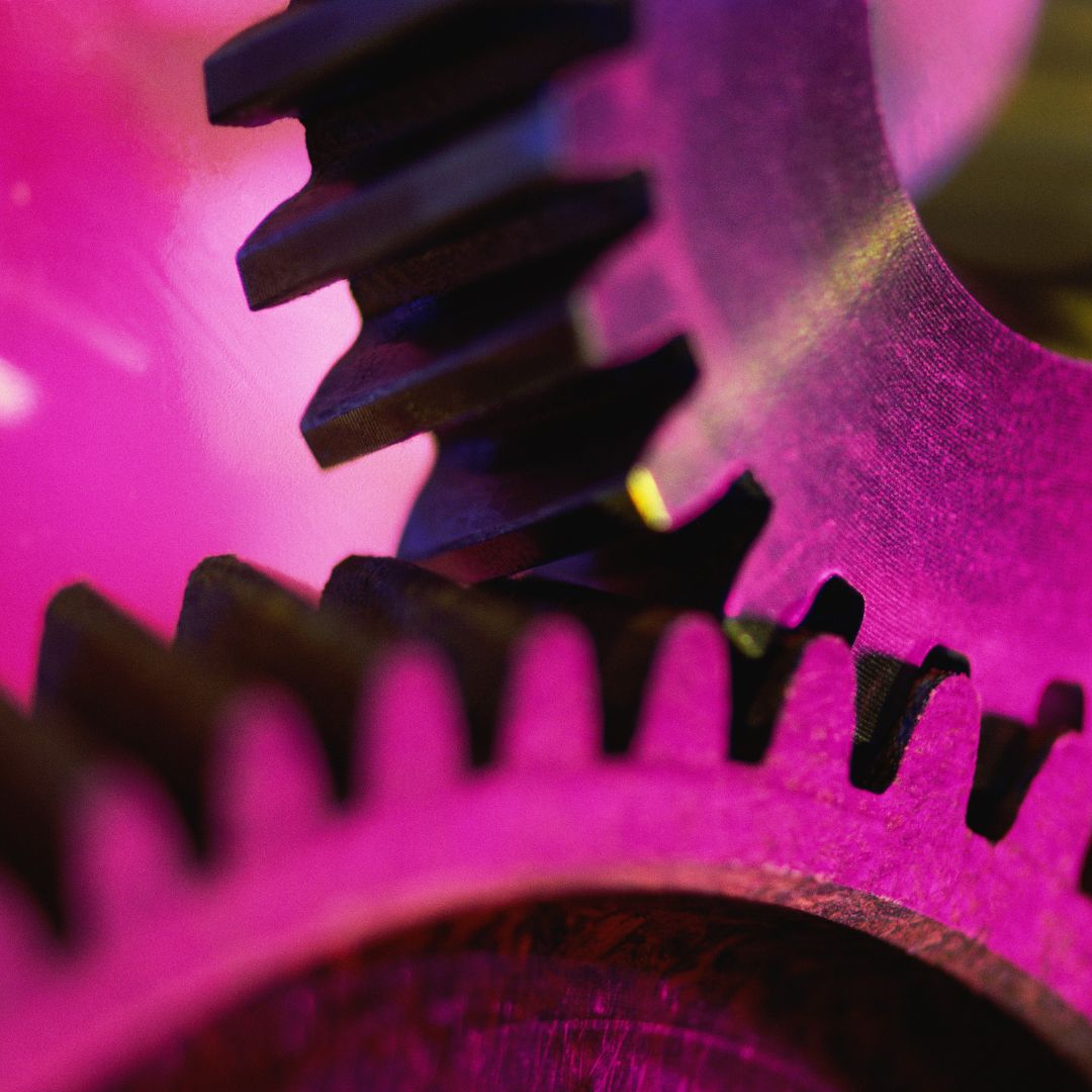 Two metal gears in a pink lights.