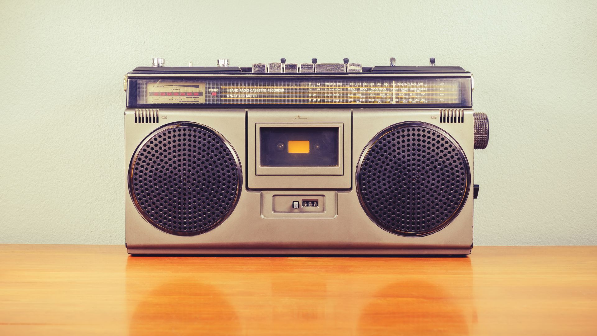Silver and gray boombox against a wall on a hardwood floor.
