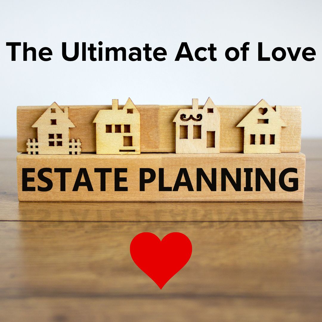 Title 'The Ultimate Act of Love' in black font. Below it, is a series of houses carved in a wooden relief with ESTATE PLANNING below it. It sits on a varnished wooden table. A red heart rests below it.