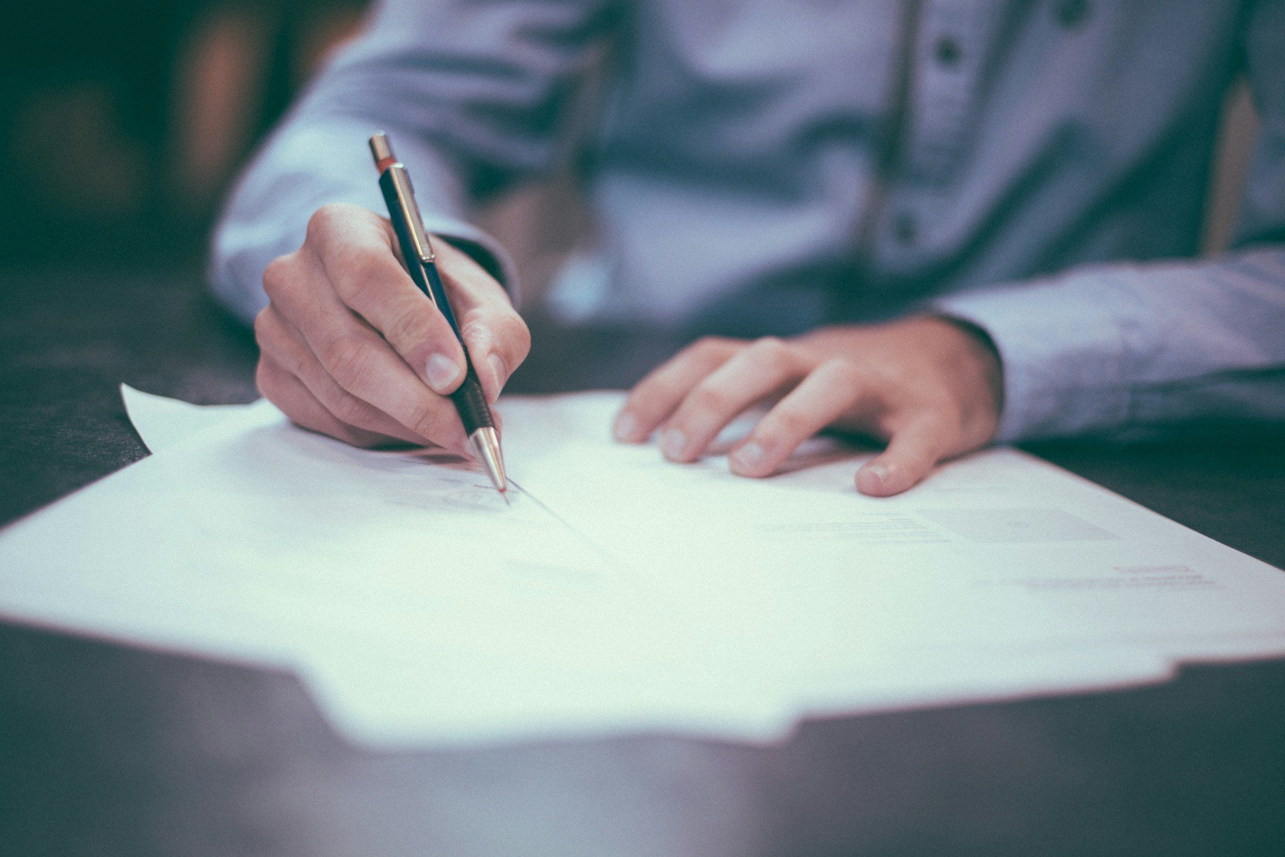 Person filling out a paper form with a pen.